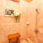 Small bench, Tv, and vase of flowers inside the shower of the Fleur De Lis Suite.