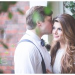 The groom is gently kissing the bride on her forehead as she blushes.