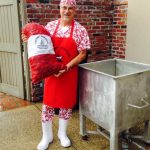 Chef Bucks holding crawfish bag ready to boil, in his red apron and signature red polkadot outfit.