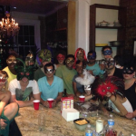 Everyone gathered in the kitchen with their mardi gars on having drinks.