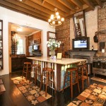 Hardwood floors, bar stools that line along side the island, stainless steel stove, and mounted TV above the fireplace in the grand kitchen.